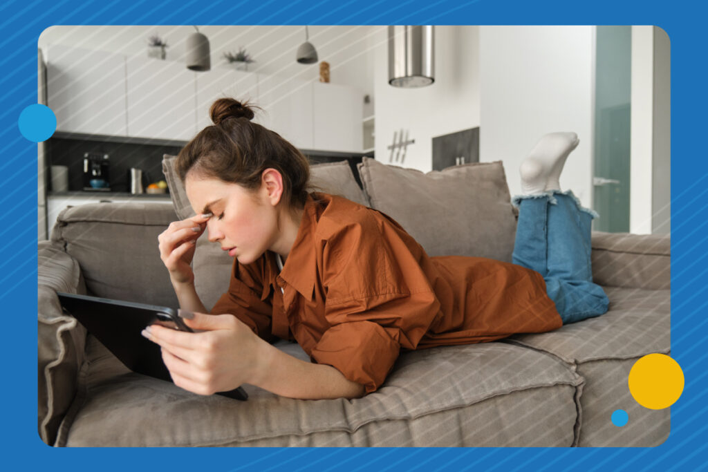 A woman lies on a couch while having a headache.